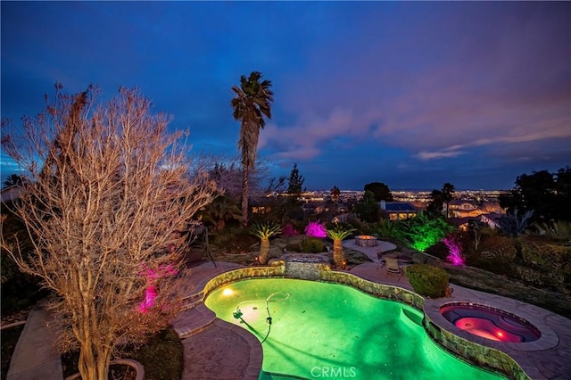 pool at dusk with an in ground hot tub