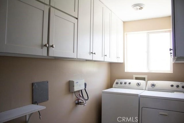 clothes washing area featuring independent washer and dryer and cabinets