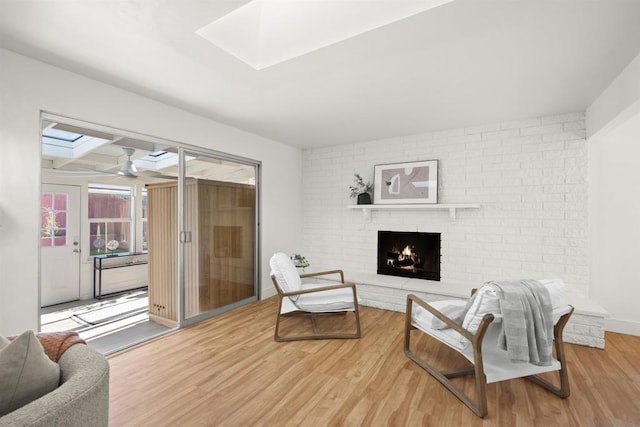 sitting room with ceiling fan, a skylight, a fireplace, and hardwood / wood-style flooring