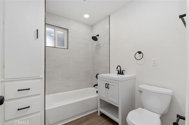 full bathroom with toilet, tiled shower / bath, hardwood / wood-style floors, and vanity