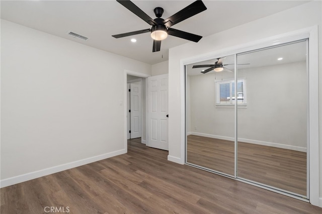 unfurnished bedroom with ceiling fan, a closet, and hardwood / wood-style flooring