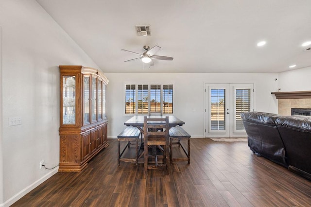 dining space featuring ceiling fan, french doors, dark hardwood / wood-style flooring, and a tiled fireplace