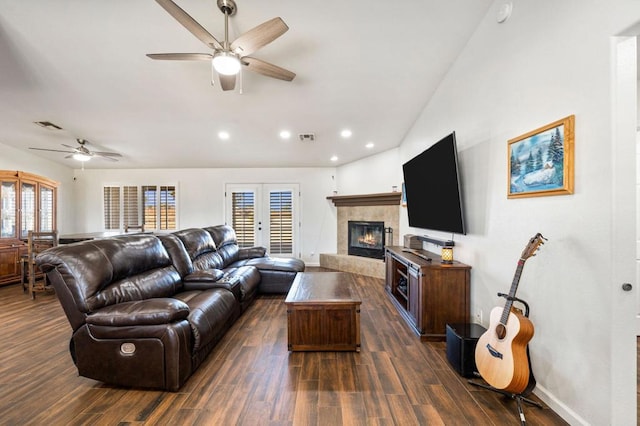 living room featuring ceiling fan, dark wood-type flooring, a wealth of natural light, and a tiled fireplace