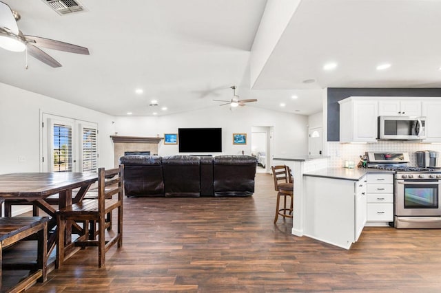 kitchen with white cabinets, appliances with stainless steel finishes, lofted ceiling, decorative backsplash, and kitchen peninsula