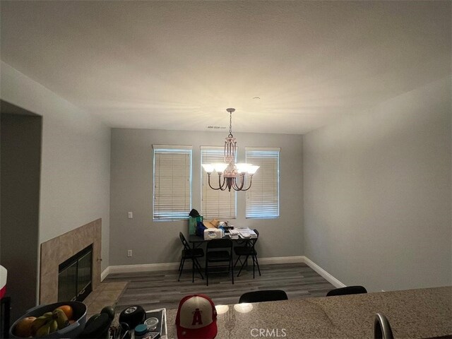 dining area with dark wood-type flooring, a chandelier, and a fireplace