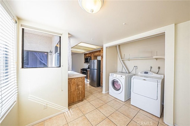 washroom with light tile patterned flooring, plenty of natural light, and washing machine and clothes dryer