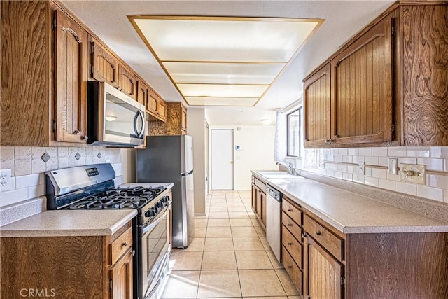 kitchen featuring light tile patterned floors, sink, backsplash, and appliances with stainless steel finishes