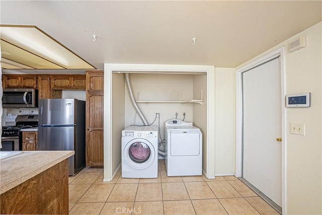 laundry area with independent washer and dryer and light tile patterned flooring