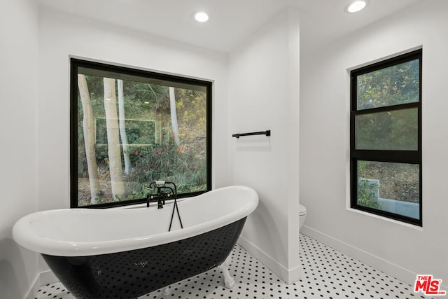 bathroom featuring toilet, tile patterned floors, and a bathtub