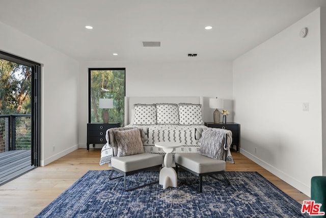 bedroom with access to exterior, light hardwood / wood-style floors, and multiple windows