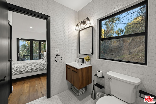 bathroom with tile walls, toilet, vanity, and hardwood / wood-style floors