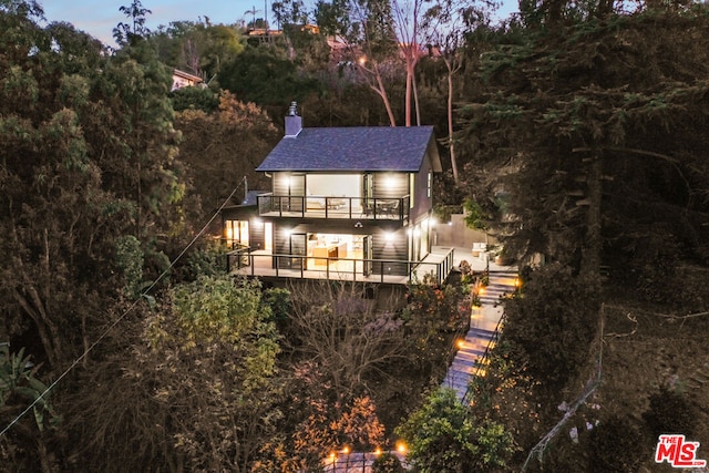 back house at dusk featuring a balcony