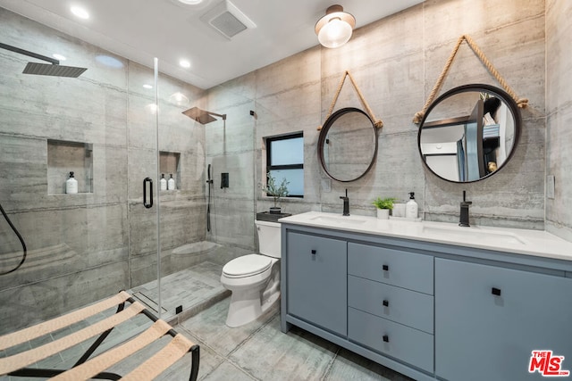 bathroom with toilet, vanity, tile walls, and a shower with door