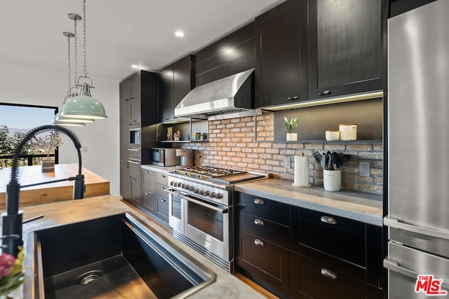 kitchen featuring wall chimney exhaust hood, stainless steel appliances, sink, hanging light fixtures, and backsplash