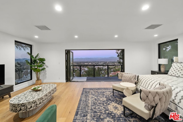 bedroom featuring light wood-type flooring, floor to ceiling windows, and multiple windows