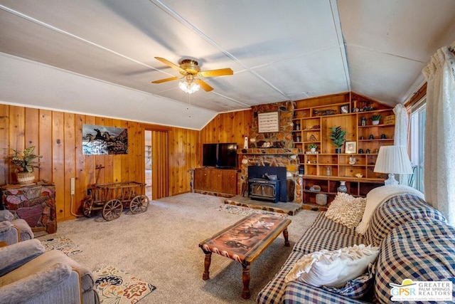 carpeted living room featuring ceiling fan, lofted ceiling, wood walls, built in features, and a wood stove