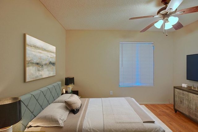 bedroom with light wood-type flooring, ceiling fan, and a textured ceiling