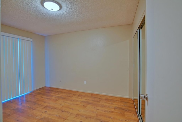 unfurnished room featuring light hardwood / wood-style floors and a textured ceiling