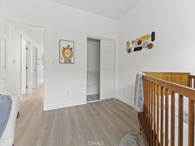 bedroom featuring light wood-type flooring, a closet, and a nursery area