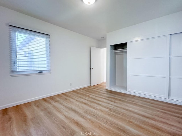 unfurnished bedroom featuring light wood-type flooring and a closet