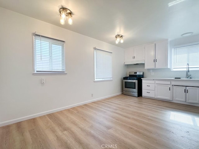 kitchen featuring white cabinetry, sink, stainless steel stove, and light hardwood / wood-style floors