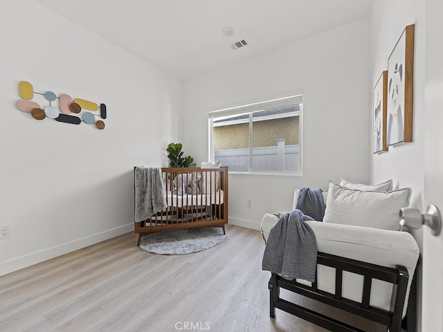 bedroom featuring light hardwood / wood-style flooring and a crib