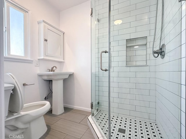 bathroom with toilet, sink, and a shower with shower door