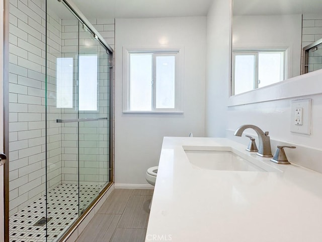 bathroom with a wealth of natural light, toilet, vanity, and an enclosed shower