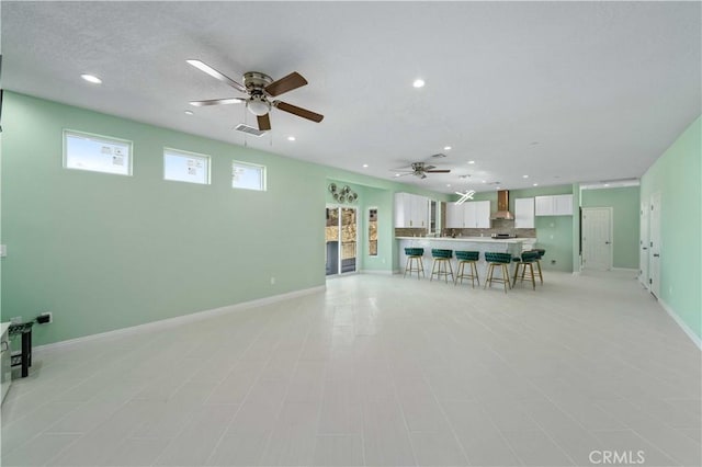 unfurnished living room with ceiling fan and a textured ceiling