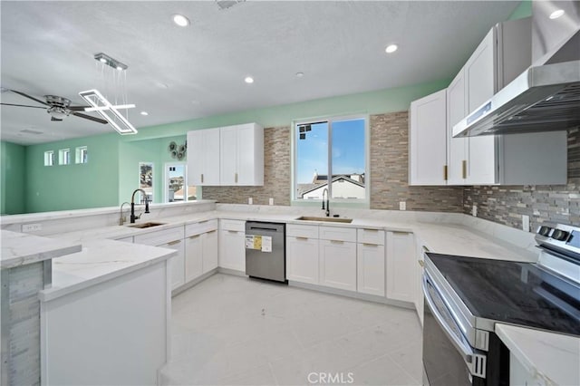 kitchen with appliances with stainless steel finishes, sink, white cabinetry, and wall chimney range hood