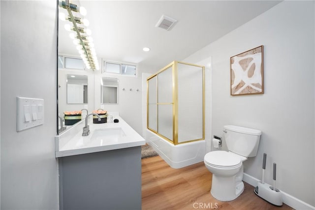 full bathroom with hardwood / wood-style floors, shower / bath combination with glass door, vanity, and toilet