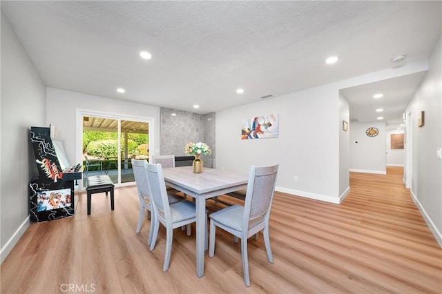 dining space with a textured ceiling and light hardwood / wood-style floors