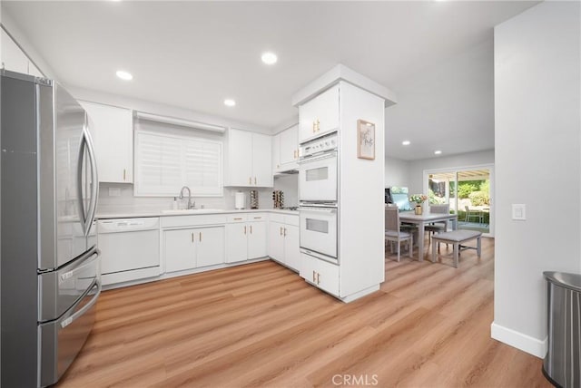 kitchen featuring sink, white appliances, and white cabinetry