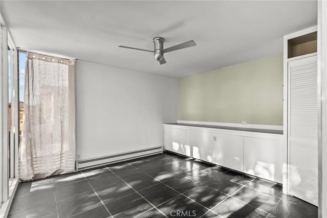 empty room featuring ceiling fan, a baseboard radiator, and dark tile patterned flooring