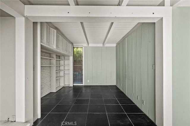 interior space with beam ceiling, built in shelves, and wood walls