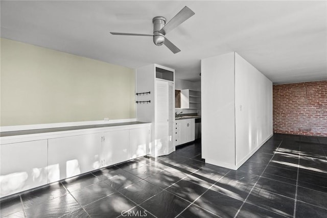 interior space featuring ceiling fan, sink, and brick wall