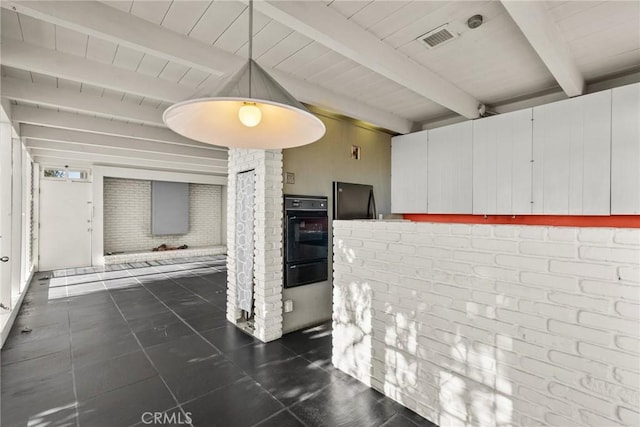 interior space with brick wall, dark tile patterned floors, and beamed ceiling