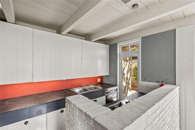 kitchen featuring beam ceiling, white cabinets, sink, and hardwood / wood-style flooring