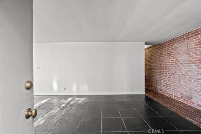 unfurnished room featuring brick wall