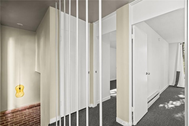 hallway with a baseboard heating unit and dark colored carpet