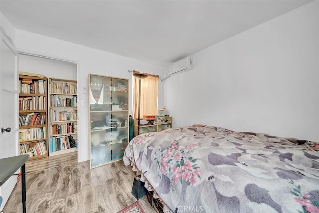 bedroom featuring hardwood / wood-style floors and a wall mounted air conditioner