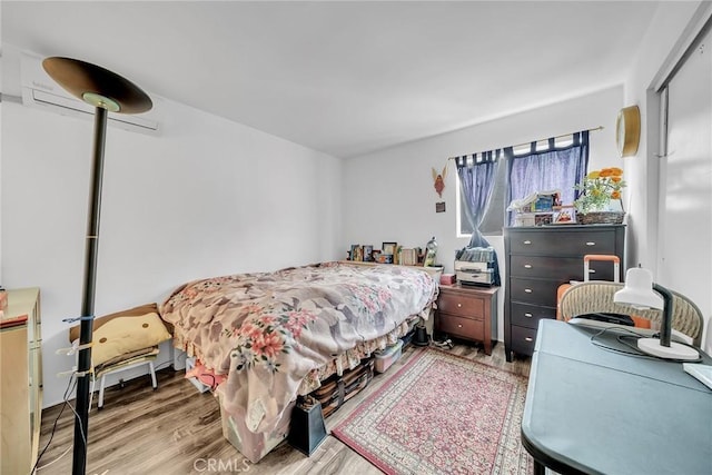 bedroom with hardwood / wood-style floors and an AC wall unit