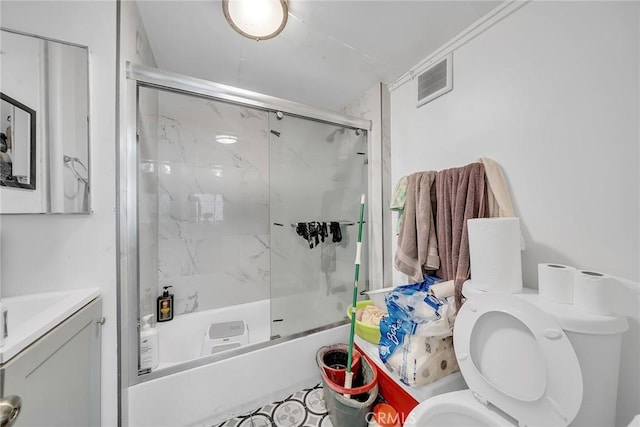 bathroom with toilet and shower / bath combination with glass door