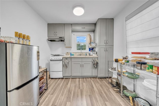 kitchen with gray cabinets, light hardwood / wood-style floors, gas range gas stove, sink, and stainless steel fridge