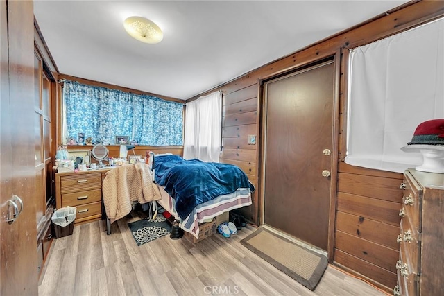 bedroom featuring wooden walls and light hardwood / wood-style floors