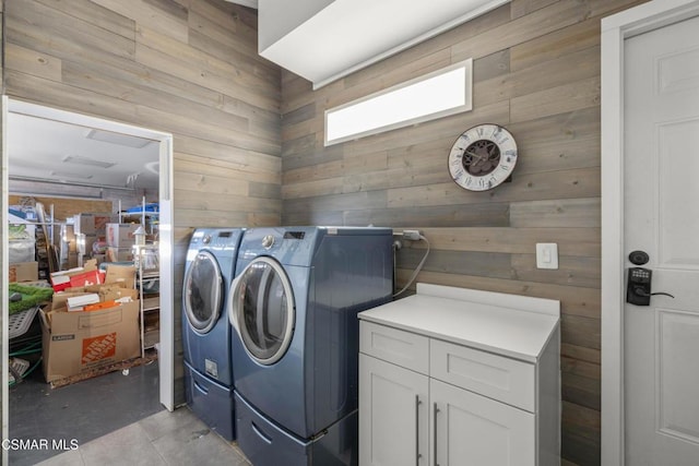 laundry room with wood walls, cabinets, light tile patterned floors, and washing machine and clothes dryer