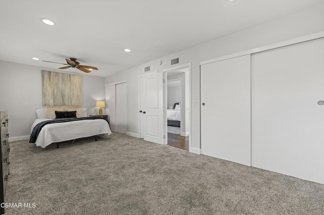 bedroom with ceiling fan, two closets, and dark carpet