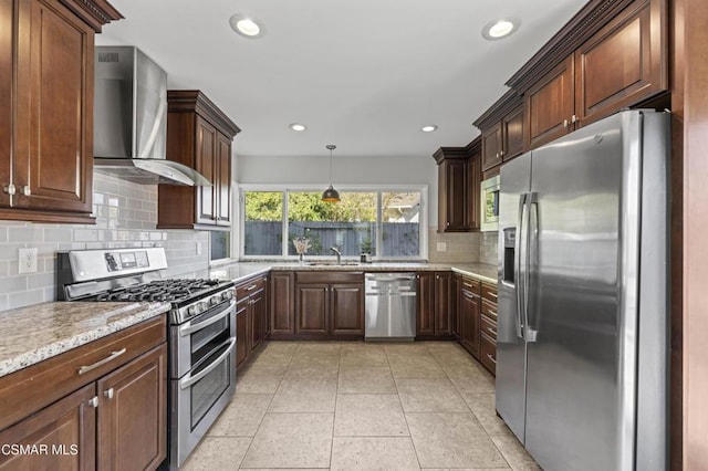 kitchen with light tile patterned floors, stainless steel appliances, decorative backsplash, hanging light fixtures, and wall chimney range hood