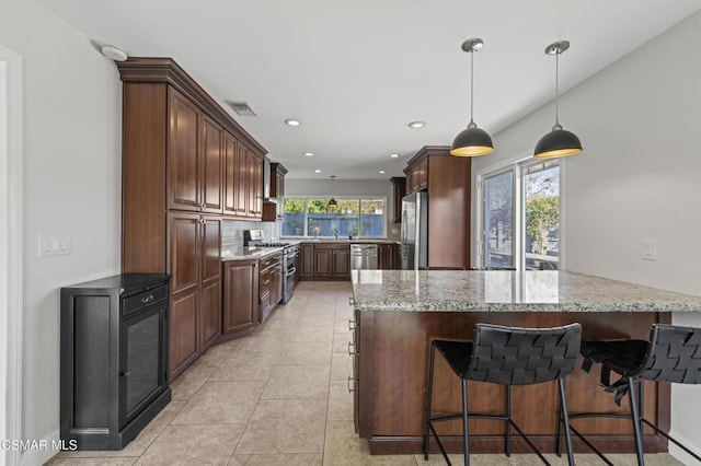 kitchen with light stone countertops, plenty of natural light, kitchen peninsula, and stainless steel appliances