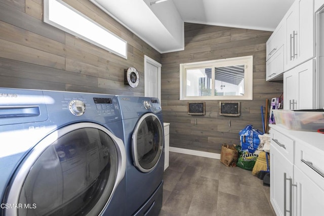 laundry room with cabinets, wood walls, and washing machine and dryer